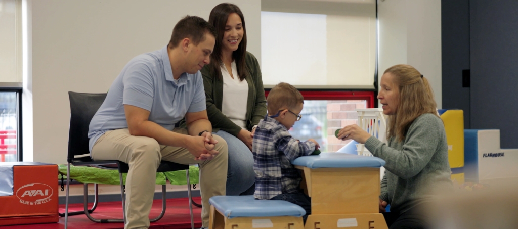 Parents watch as son works with therapist