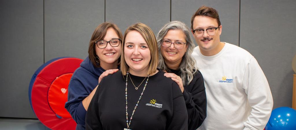 Three women and one male staff member pose in a treatment room